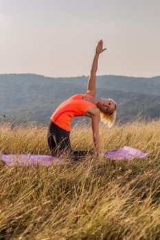 Beautiful woman doing yoga in the nature,variation of Camel pose.Image is intentionally toned.