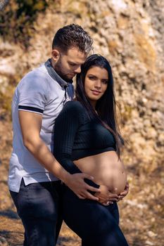 Photo of a young couple with their hands on the belly of the woman who is pregnant