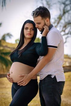 Photo of a young couple with their hands on the belly of the woman who is pregnant