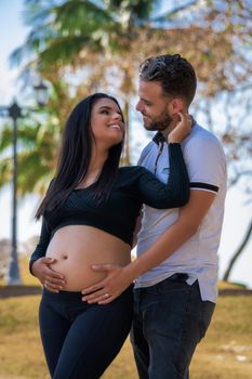Photo of a young couple with their hands on the belly of the woman who is pregnant