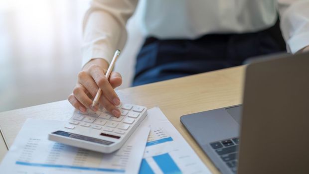 woman calculating individual income tax from financial document during note some data to sticky on window glass with calculator.