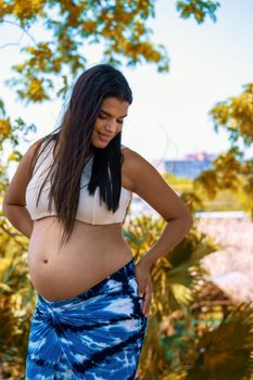 Outdoor photo of a young pregnant woman with long hair