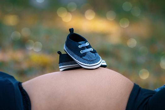 Photos of a pair of tiny shoes on a pregnant woman's tummy