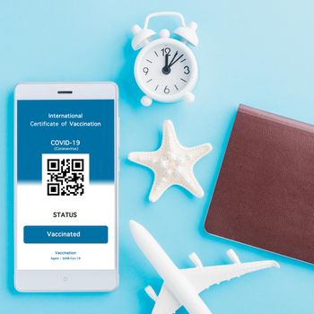 Model airplane, passport and immunity pass are arranged application on smartphone on blue background, Travel concept during Covid-19 pandemic digital International Vaccination Certification concept