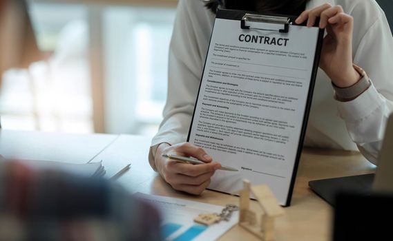 Sale purchase contract to buy a house, Real estate agent are presenting home loan and giving keys to customer after signing contract to buy house with approved property application form.