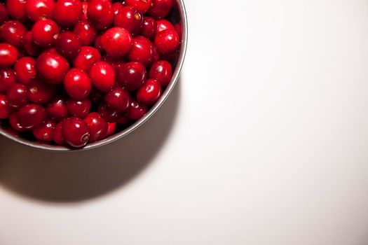 Bowl of cherries on a white background. Red cherries. Bowl placed on the top left corner of the frame