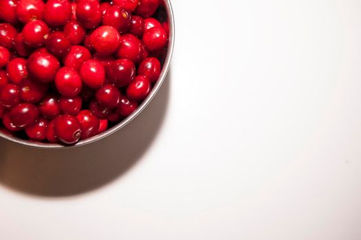 Bowl of cherries on a white background. Red cherries. Bowl placed on the top left corner of the frame