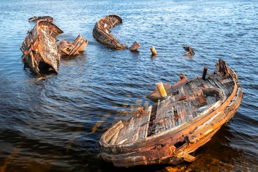 Rusty old abandoned wooden fishing boat which is pulled out on the coast of the sea in Teriberka