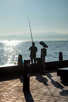 silhouette of man fishing on the seashore