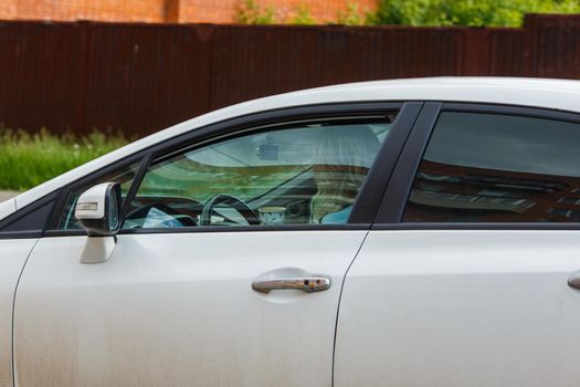 unidentifiable blonde long hair woman driving white car with paper coffee cup at summer day light