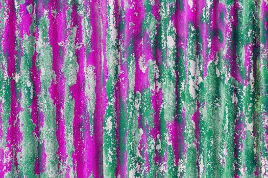 colorful motley peeled off green and pink paint layers on corrugated zinc coated steel sheet - full frame background and texture