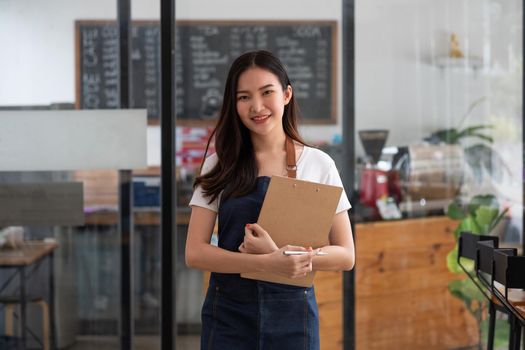 Startup successful small business owner woman beauty girl standing in coffee shop restaurant. Portrait of smiling asian woman barista cafe local owner.