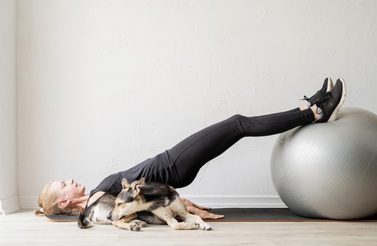 Sport and healthy lifestyle concept. Young sportive woman in black clothes sitting on the fitball warming out before workout