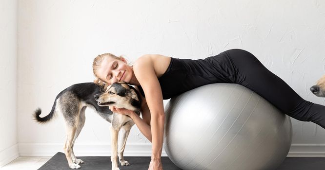 Sport and healthy lifestyle concept. Young sportive woman embracing her mixed breed dog laying on the floorat home