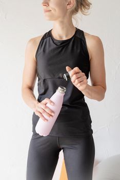 Sport and healthy lifestyle concept. Close up of woman hands holding thermos bottle