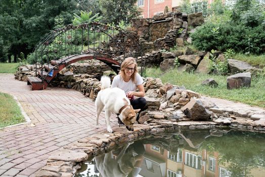 young caucasian woman walking her dog in a summer park