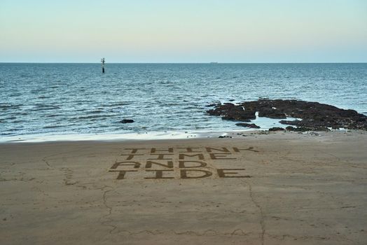 Think time and tide has been drawn in the sand on a beach to warn beachgoers to not get caught out by the tide.