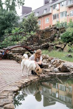 young caucasian woman walking her dog in a summer park