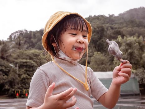 Cute little girl eating ice cream outdoors on a hot summer day.