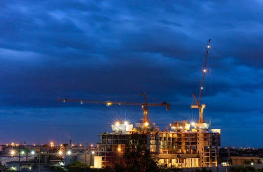 Construction site with cranes in cloudy night