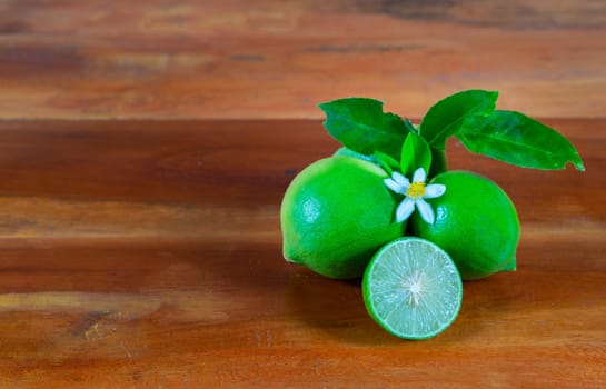 Flower, cut and whole limes on wooden background