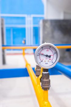 Closeup of manometer for measuring gas pressure. Pipes and valves at industrial plant.