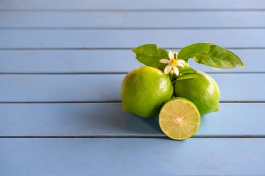 Flower, cut and whole limes on blue wooden background