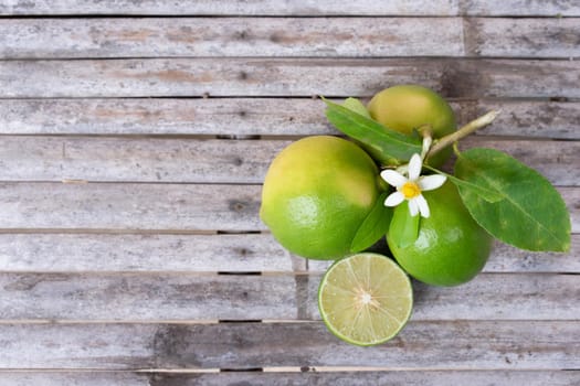 Top view of flower, cut and whole limes on wooden background