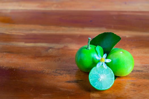 Flower, cut and whole limes on wooden background