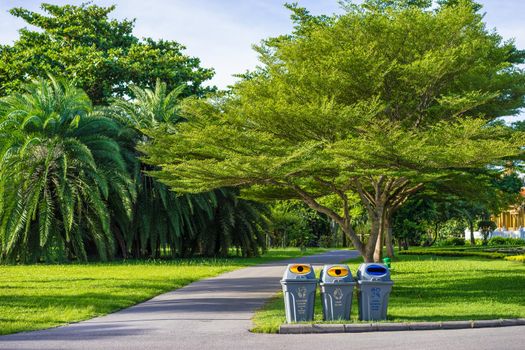 Three trashcans in a park with green tree and plants background in public park