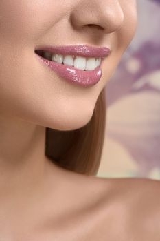 Flirty smile. Vertical cropped close up of a perfect healthy smile of a beautiful woman wearing natural pink lip gloss beauty healthcare medicine dentistry lifestyle fashion cosmetics concept