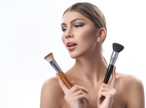 Pure beauty. Beautiful sensual woman with perfect skin wearing professional makeup holding two makeup brushes near her face looking away copyspace beauty flawless confidence cosmetics concept