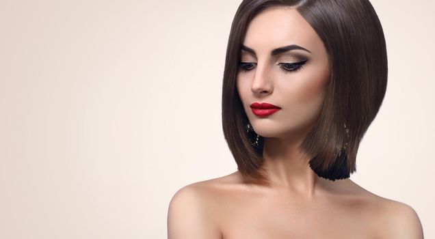 Young fashion model posing sensually looking away wearing black dress and evening makeup with red lips and smoky eyes copyspace beauty fashion style elegance cosmetics concept.