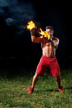Vertical shot of a young male fighter with stunning sexy hot muscular body and six-pack working out at night his boxing gloves burning with fire sport sportsman champion concentration ambitious force.