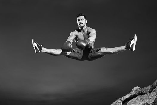 Monochrome shot of a handsome fit young male gymnast jumping high doing splits in the air copyspace sports fitness lifestyle flexible stretching legs energetic activity gymnastics jump fly concept.