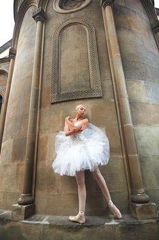 Low angle vertical shot of a beautiful ballerina standing on the wall of an old castle grace beauty statuesque elegance concept.