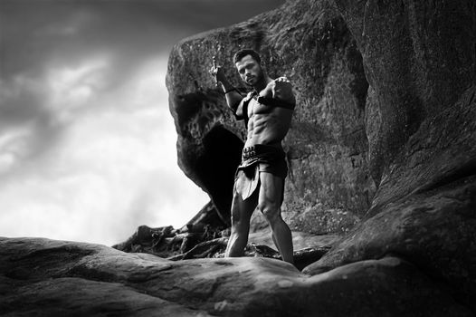 Never defeated. Low angle horizontal monochrome shot of a muscular gladiator holding out his sword to the camera copyspce on the side