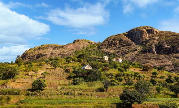 Typical Madagascar landscape - green and yellow rice terrace fields on small hills with clay houses in region near Ambositra.