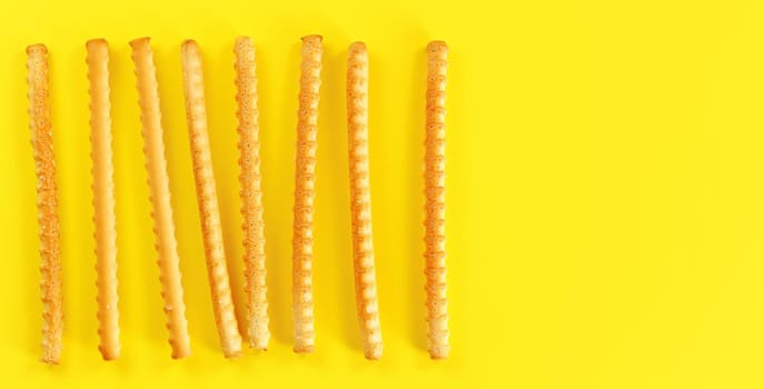 Grissini, also known as breadsticks on yellow board, view from above space for text right side.