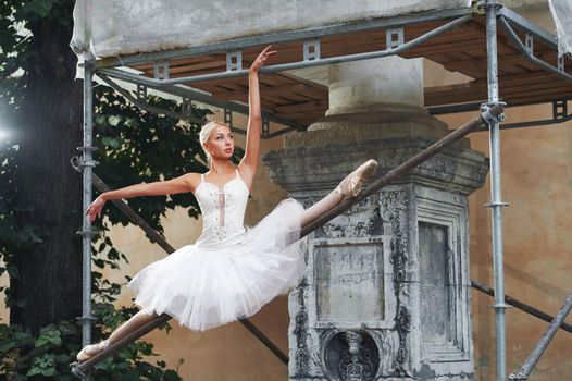 Horizontal shot of a beautiful young female ballet dancer posing gracefully on the construction site of an old building.