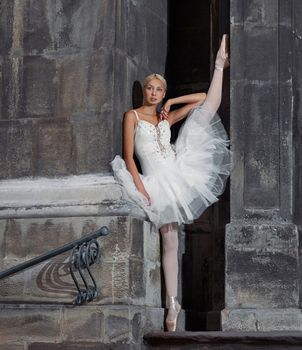 Reaching for dreams. Portrait of a beautiful female ballerina posing near an old castle with her leg raised up against the wall soft focus
