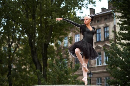 Stunning expressive ballet performance of a professional female dancer wearing black swan outfit city urban street town sensuality fierce beauty.