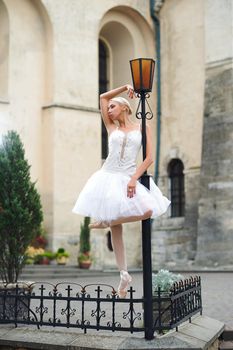 Vertical full length shot of a beautiful ballerina standing near street lamp looking away dreamily beauty urban city grace elegance
