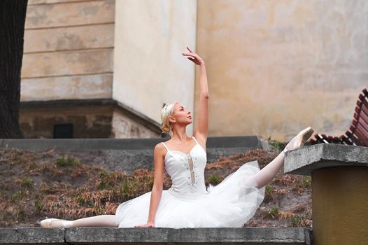 Gorgeous blonde haired ballerina doing splits while performing outdoors in the city flexible flexibility balance athletics beauty grace.