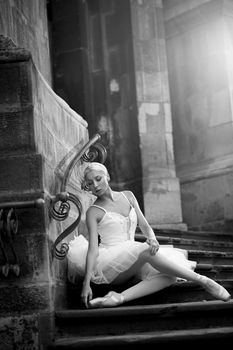 Pure elegance. Monochrome vertical soft focus shot of a blonde woman wearing ballet clothing sitting on stairs looking down sensually
