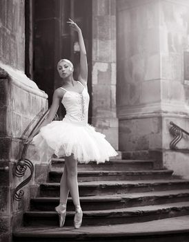 Epitome of grace and elegance. Monochrome shot of a young ballerina posing en pointe on the stairs of an old castle