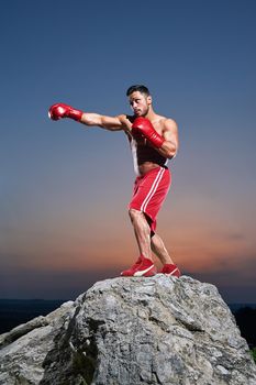 Young aggressive man working out outdoors on sunset boxing punching preparing for fighting fighter martial arts strength power training professional confidence fierce tough masculine muscular