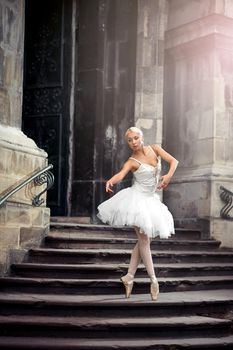 Statuesque ballerina. Young ballerina wearing all white practicing in an old castle