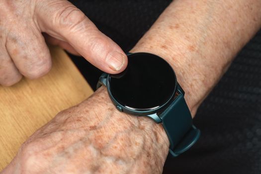 Smart watch black screen - add your graphics on elderly senior hand, closeup detail.