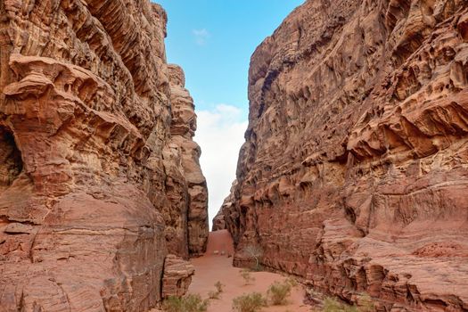 Rocky canyon with red sand on ground - Wadi Rum scenery.